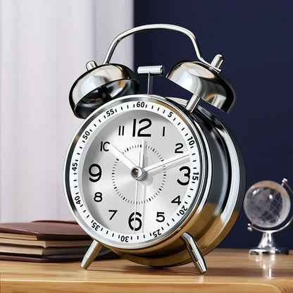 Clairly vintage twin bell alarm clock with a silver alloy frame and white face on a wooden nightstand